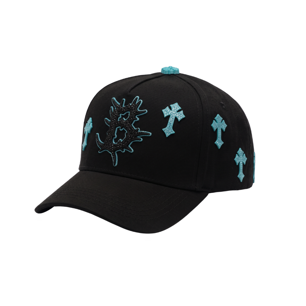 Gorra Heaven negra con cruces celestes, bordados laterales y detalles turquesa en contraste.