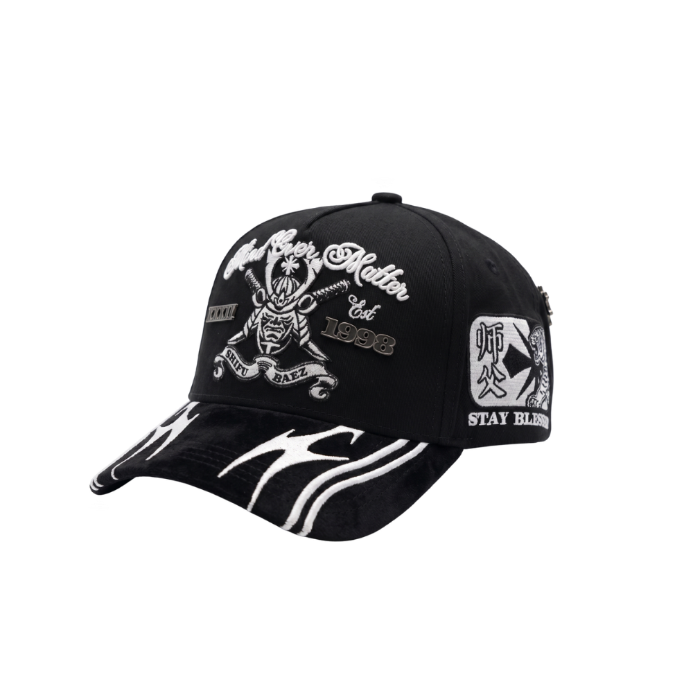 Gorra Mind Over Matter negra con bordado frontal blanco de figura central, tipografía decorativa y visera con gráficos blancos en contraste