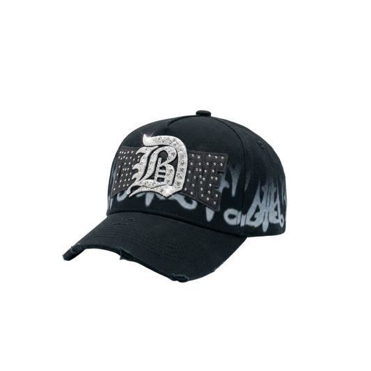 Gorra DB31 negra con logo frontal brillante tipo pedrería, detalles en contraste y efecto gráfico difuminado en blanco sobre la base