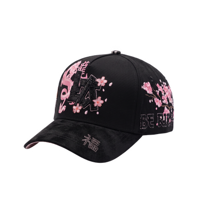 Gorra LA Japan 2.0 negra con aplique frontal LA negro, dragon y flores rosadas, grafico lateral de gato japones y visera curva negra.