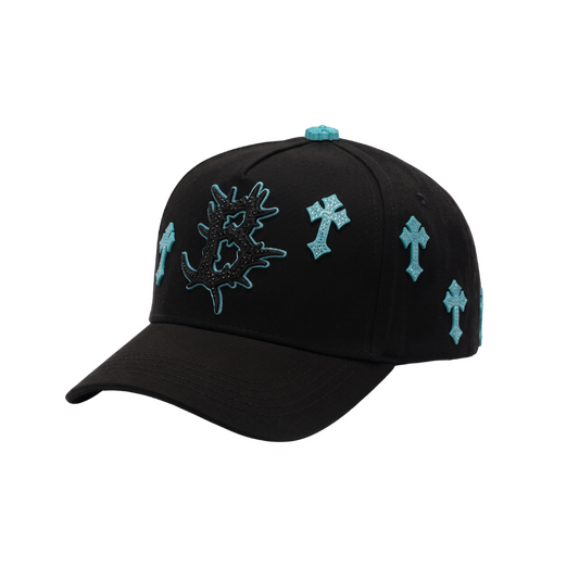 Gorra Heaven negra con cruces celestes, bordados laterales y detalles turquesa en contraste.